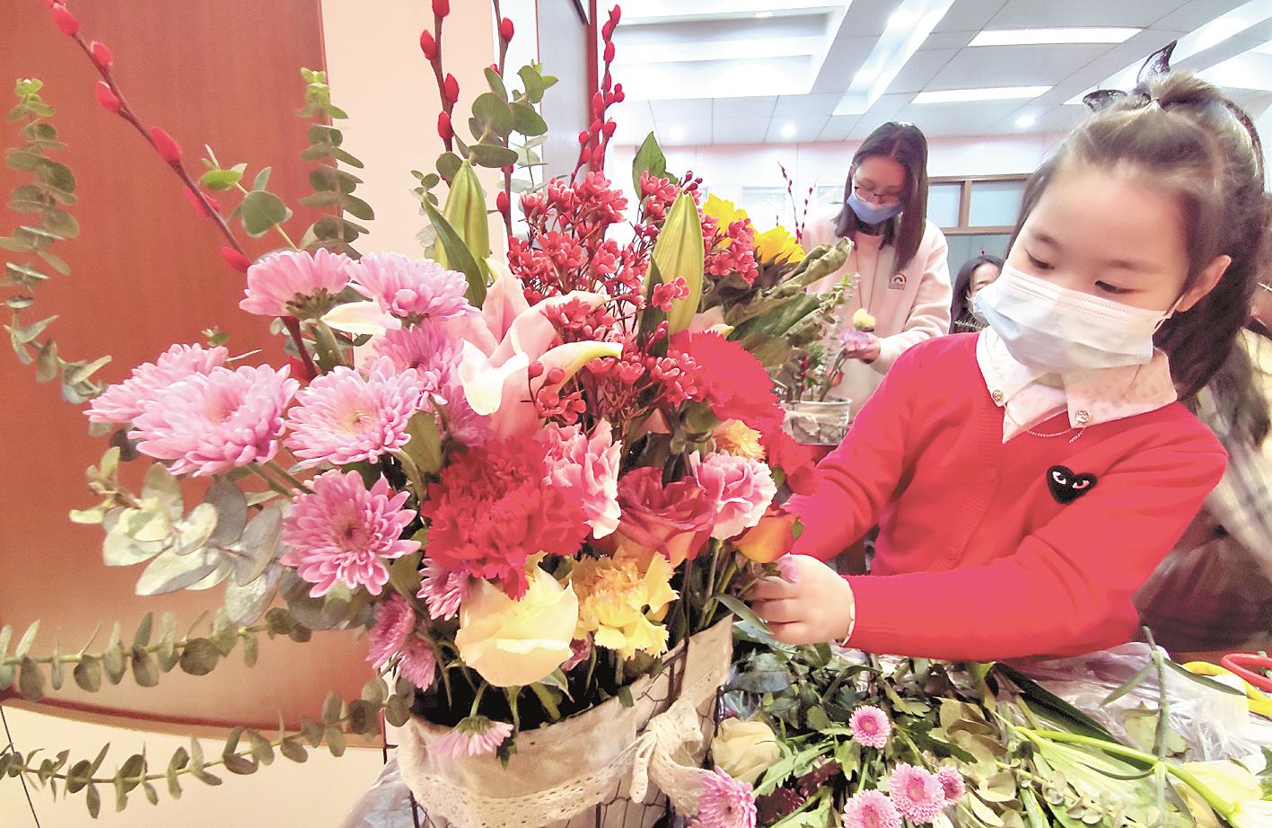 2月3日，武漢市江漢區(qū)唐家墩社區(qū)的小朋友在志愿者的指導下，插出了自己喜歡的迎春納福花籃。 （視界網(wǎng) 李長林 攝）