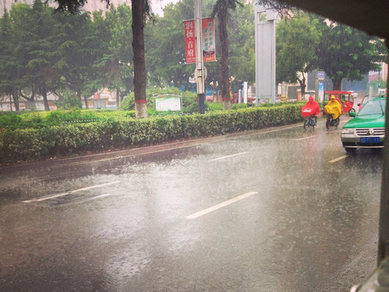 7日下午，山東棗莊市出現(xiàn)降雨，市民冒雨出行。